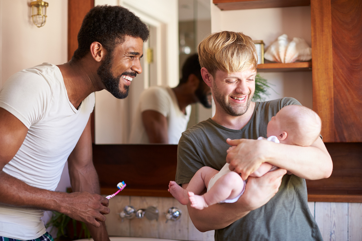 Loving Male Same Sex Couple Cuddling Baby Daughter In Bathroom At Home  Together - GoAd Media